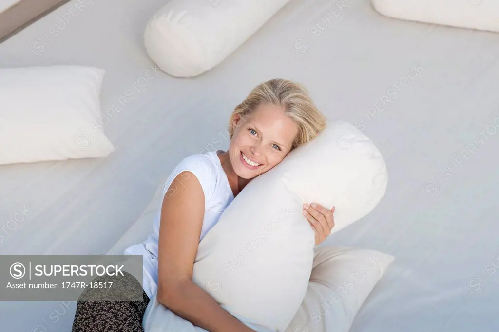 Young woman hugging pillow on bed