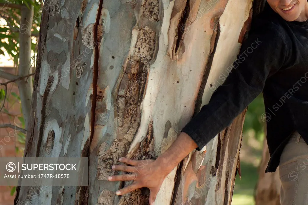 Man touching tree trunk, cropped