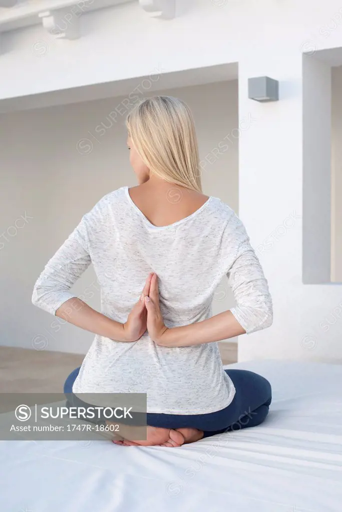 Woman doing reverse prayer position on bed, rear view