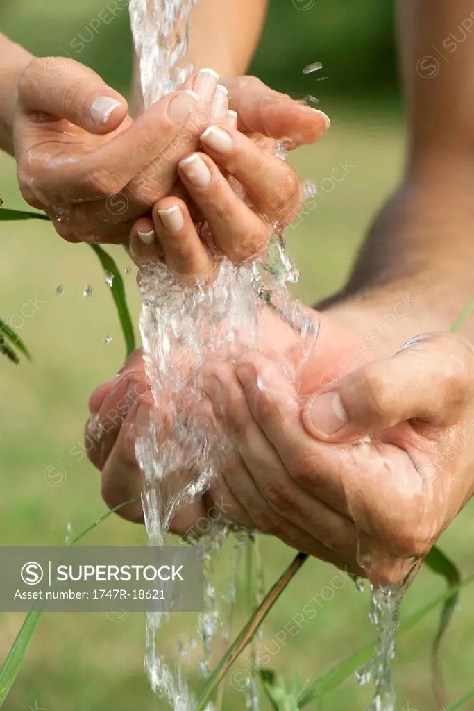 Cupped hands under running water outdoors