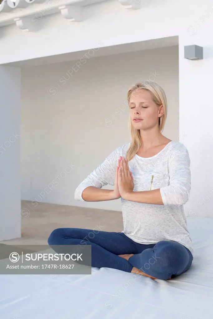Young woman sitting in prayer positon, eyes closed