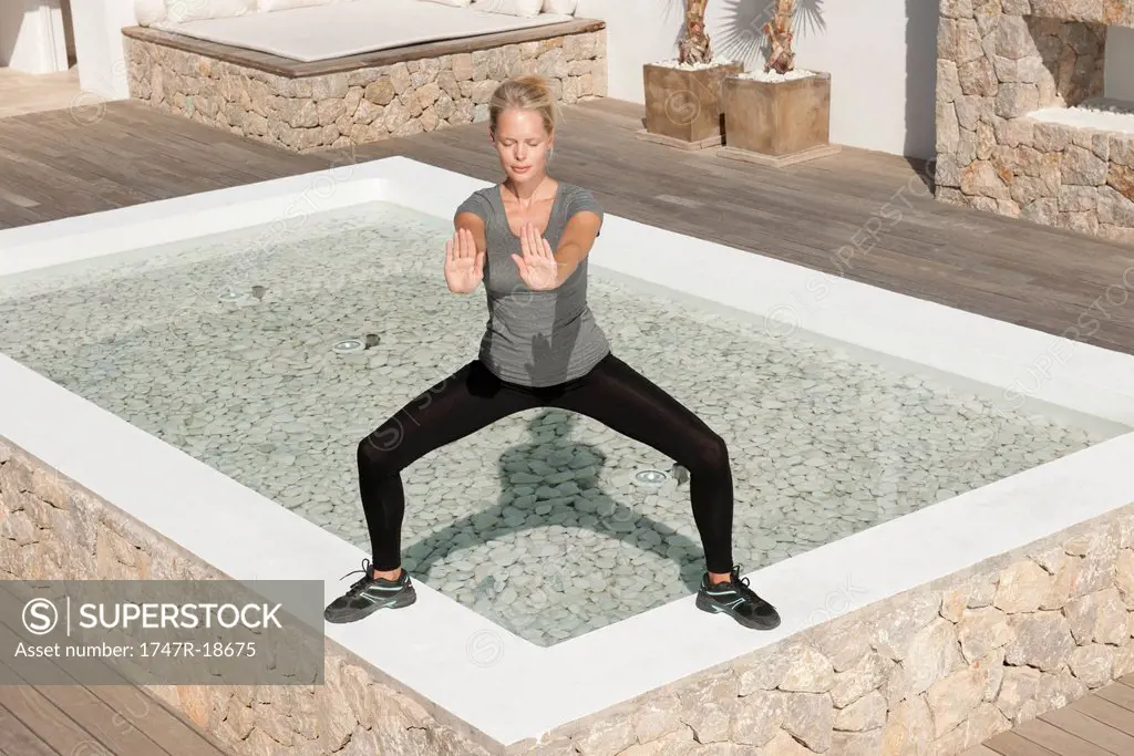 Young woman practicing tai chi chuan in patio with eyes closed