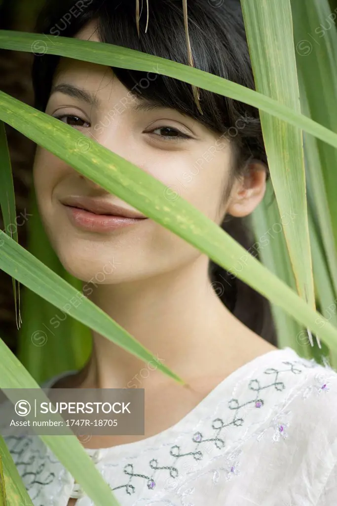 Young woman looking through foliage, portrait