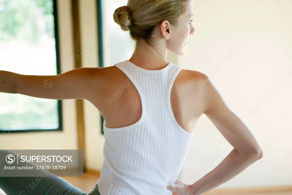 Young woman doing seated spinal twist, rear view