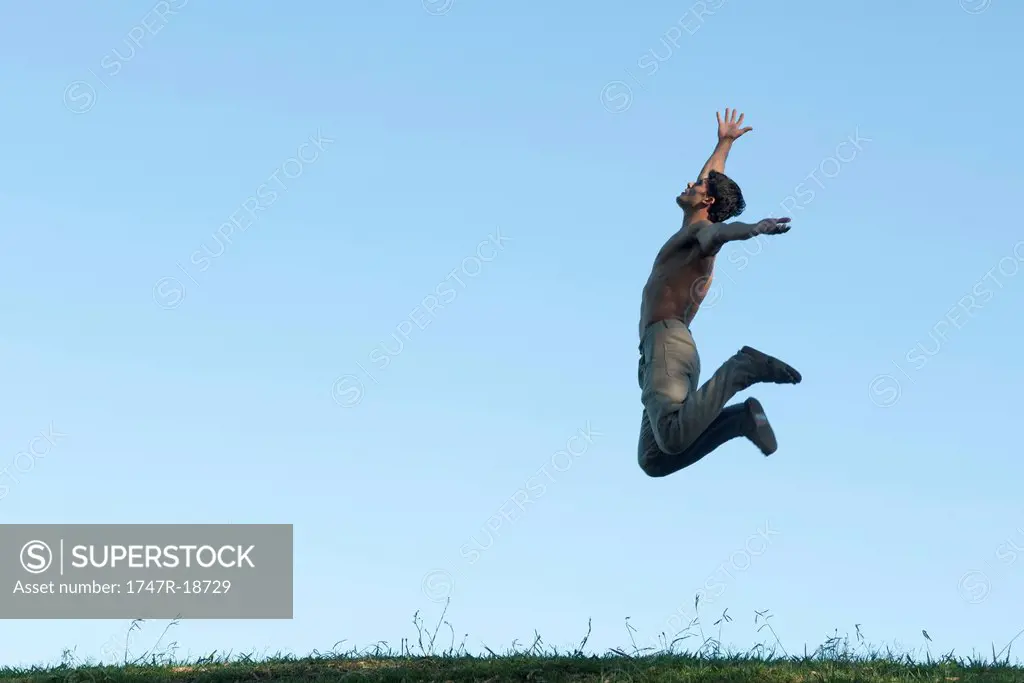 Barechested man jumping in air