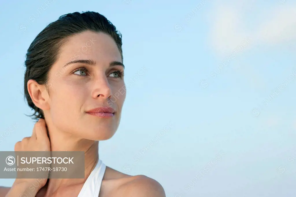 Woman touching neck, looking up in thought