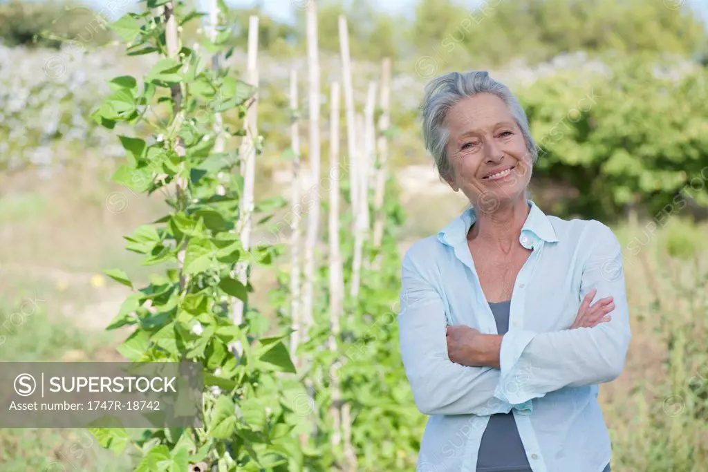 Senior woman smiling proudly in vegetable garden