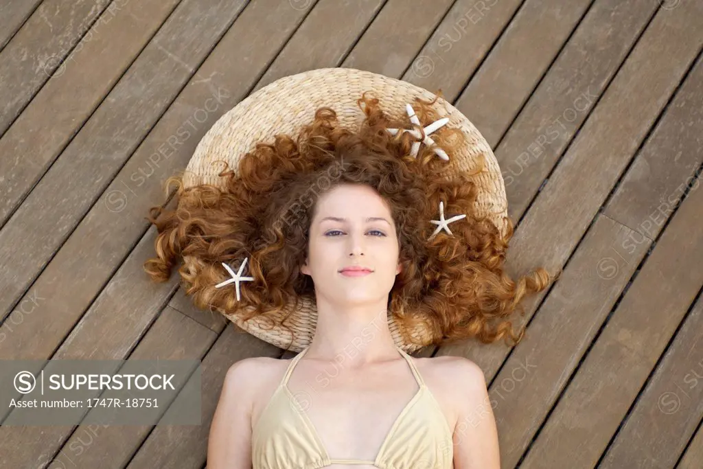 Young woman in bikini lying on deck, starfish in hair