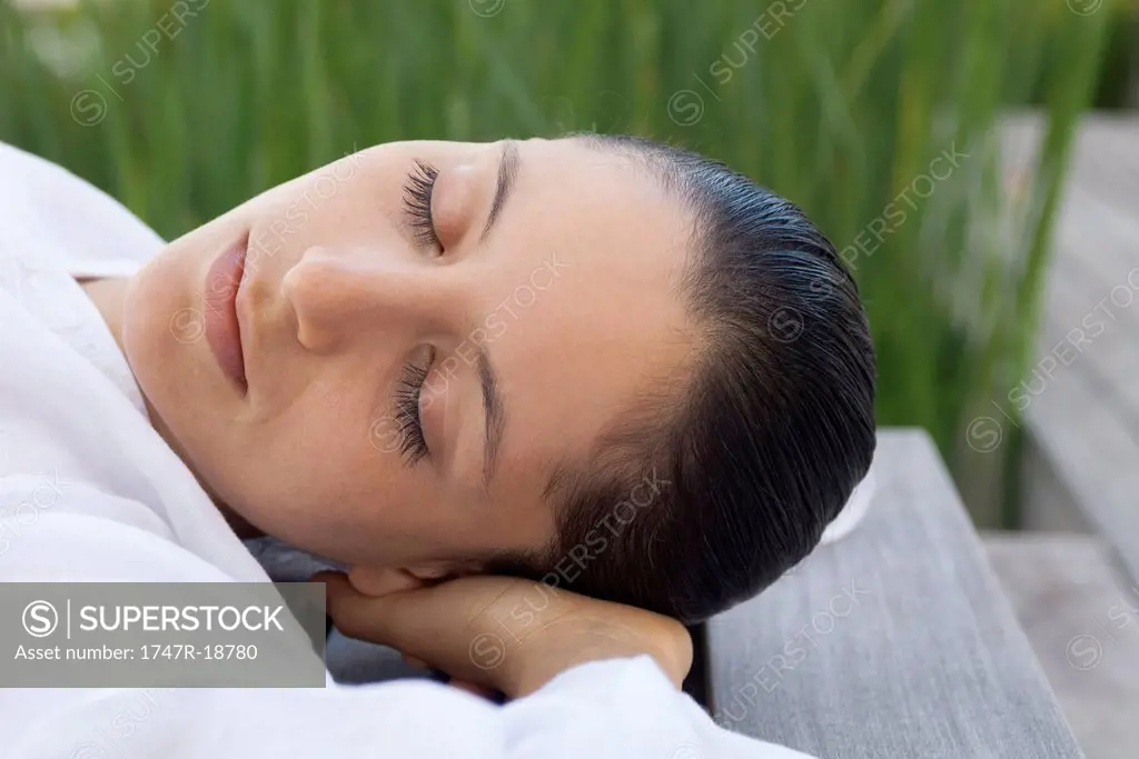 Woman lying down with hands behind head outdoors