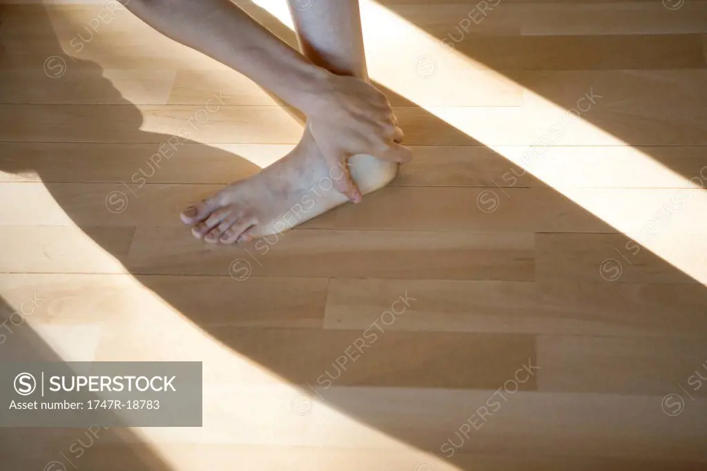 Woman touching ankle, low section, cropped