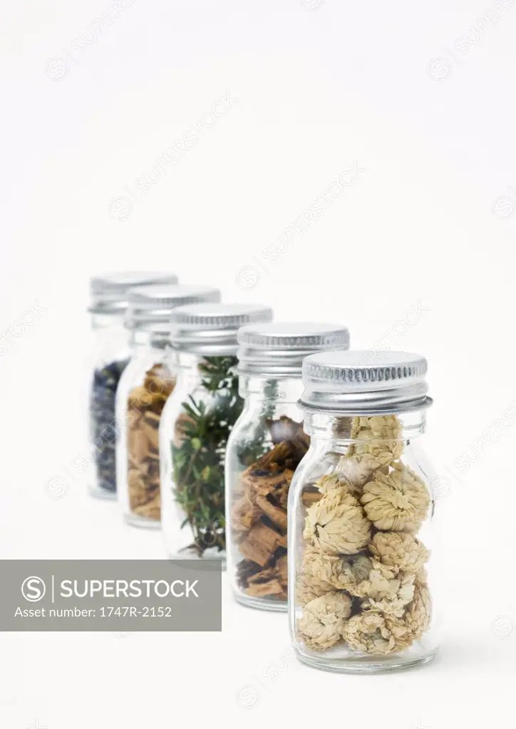Bottles containing dried flowers, herbs, and wood shavings