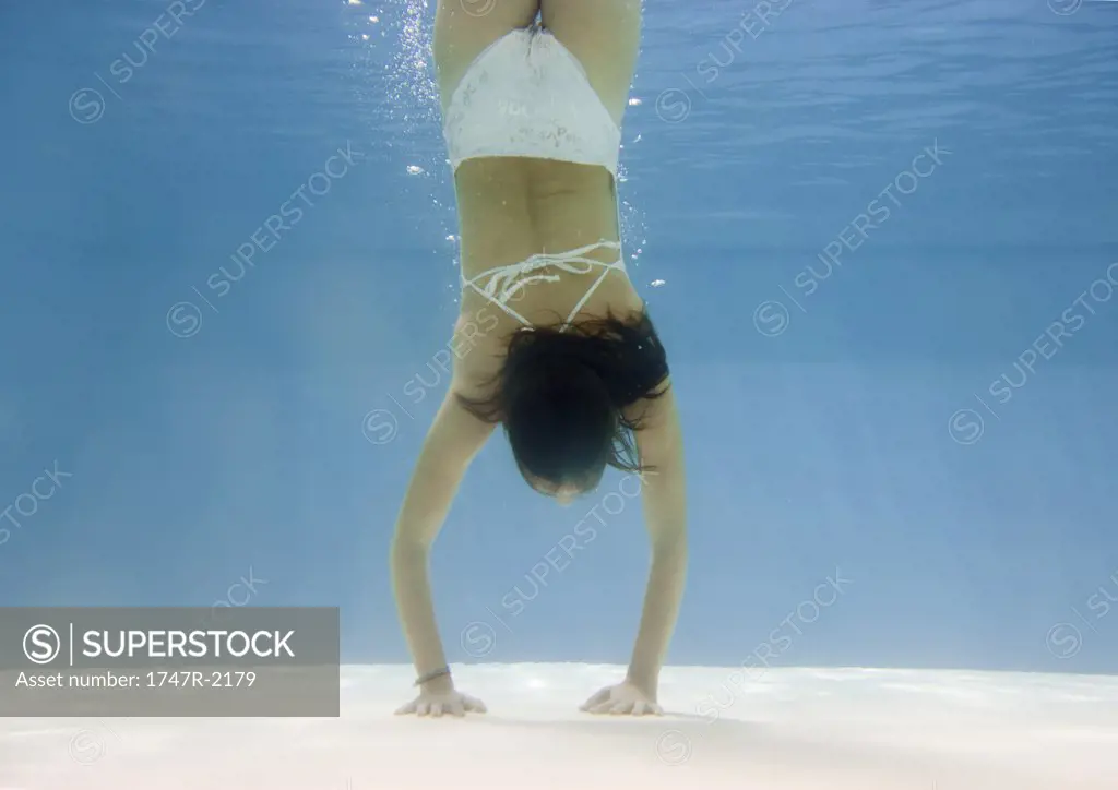 Teenage girl doing handstand underwater