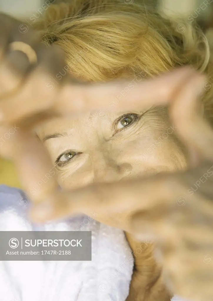 Senior woman looking at camera through finger frame