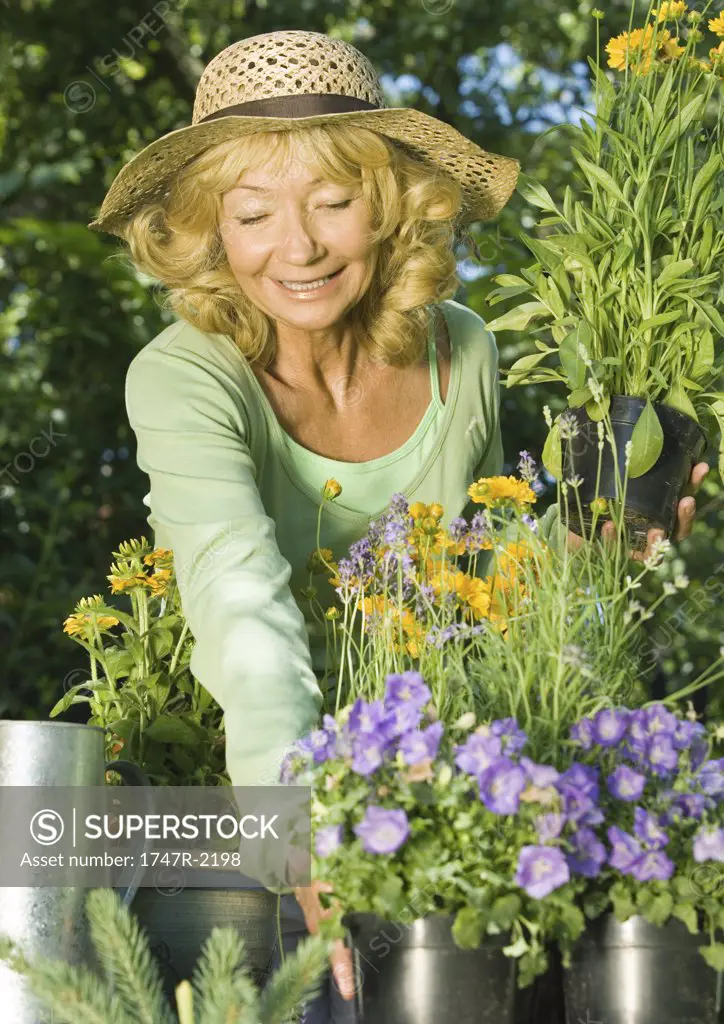 Senior woman reaching for pot of flowers