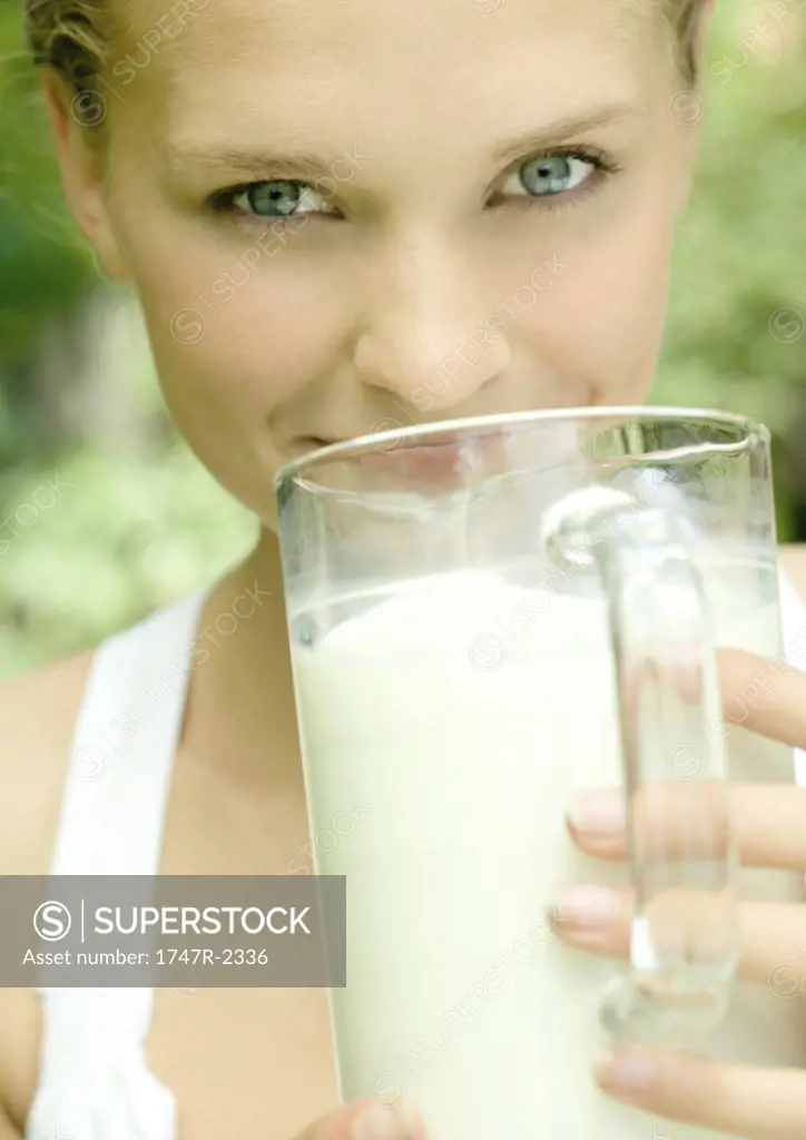 Young woman holding pitcher of milk to mouth