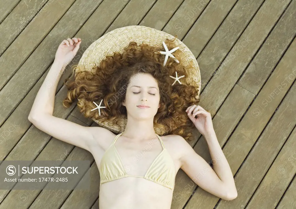 Woman lying on deck, wearing bikini, starfish in hair