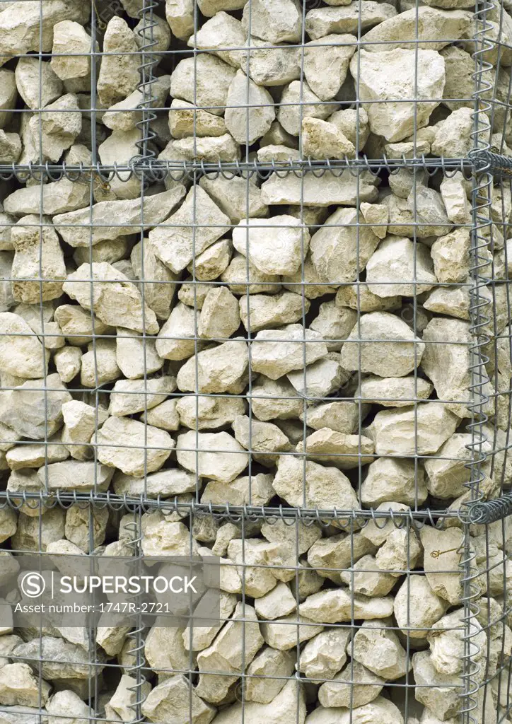Stone wall contained by wire mesh, close-up