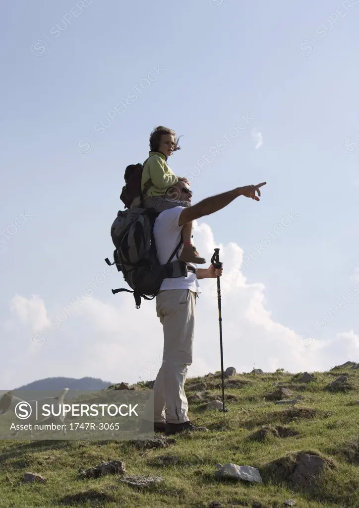 Hikers, girl riding on man's shoulders, man pointing toward distance