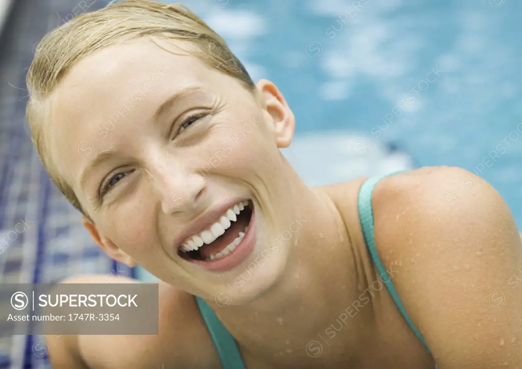 Young woman laughing, pool in background