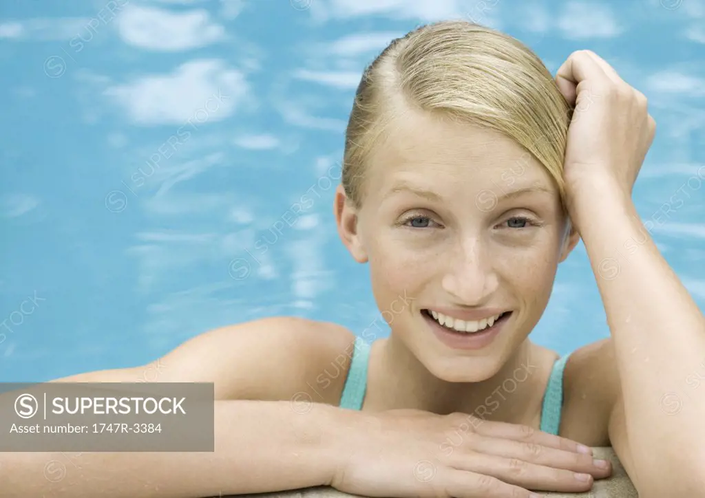 Young woman smiling, portrait, pool water in background