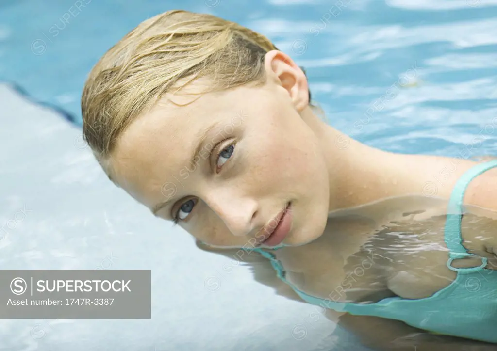 Young woman in pool, dipping face into water
