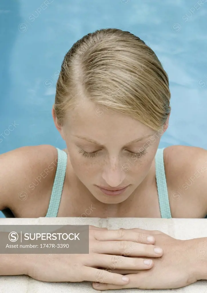 Young woman resting at edge of pool