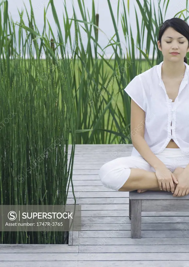 Woman sitting on deck, meditating