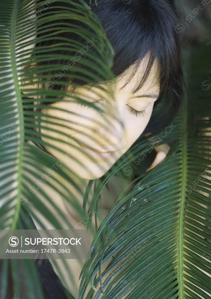 Woman standing amongst leaves, head and shoulders