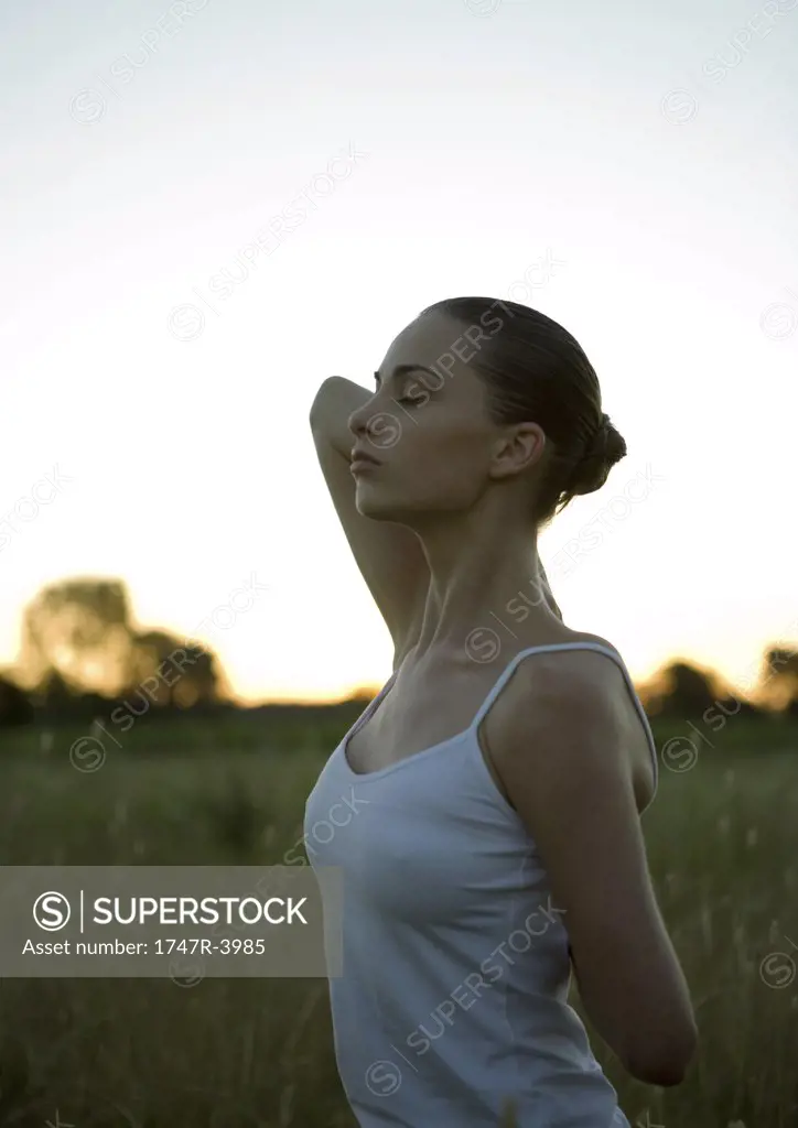 Woman stretching arms behind back, eyes closed
