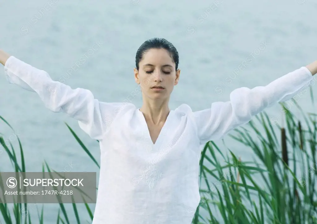 Woman stretching arms, lake in background