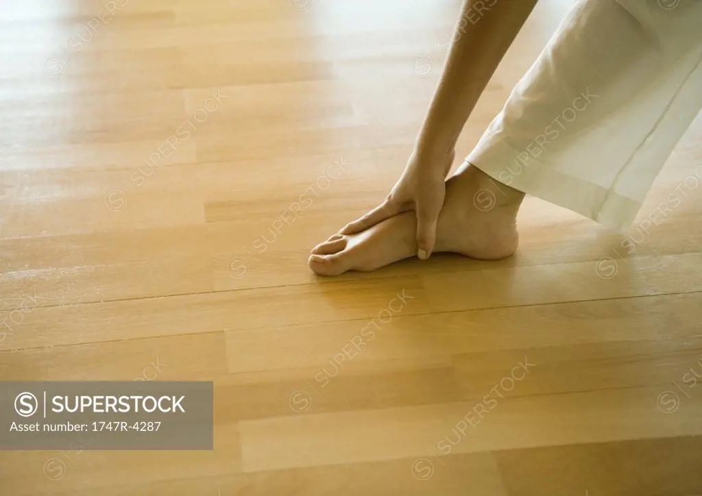 Woman doing standing forward bend, cropped view of hands and feet