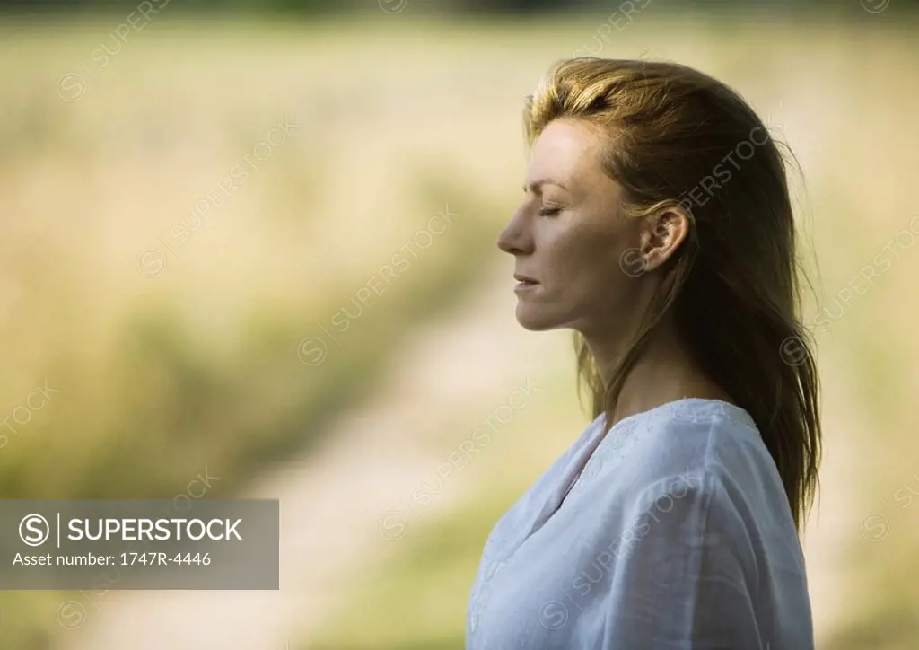 Woman outdoors with eyes closed, head and shoulders, profile