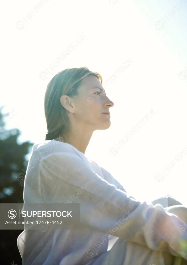 Woman sitting outdoors, low angle view