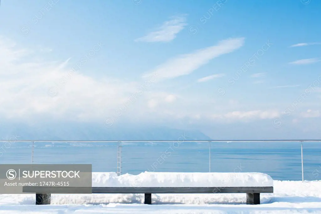 Snow-covered bench overlooking lake