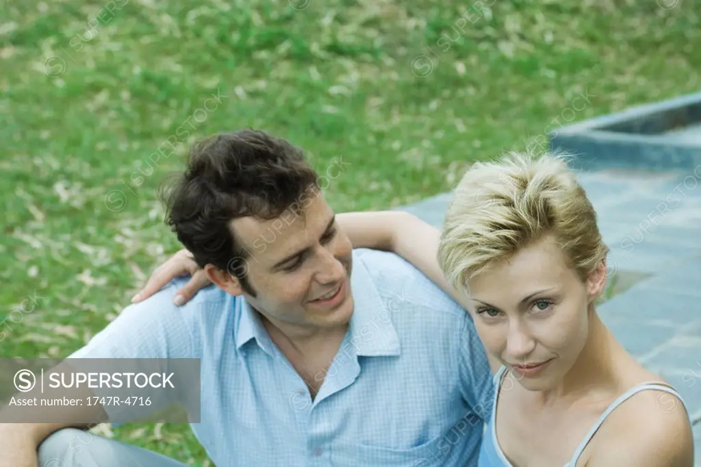 Couple sitting in backyard, man looking at woman, woman looking at camera