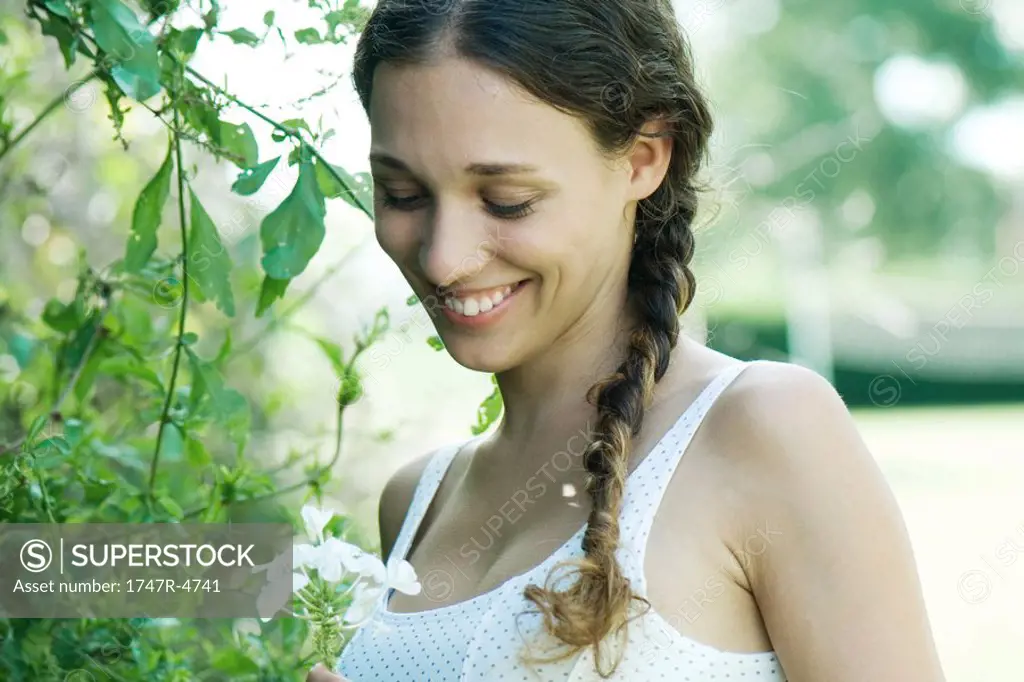 Woman standing by flowering tree, smiling, looking down