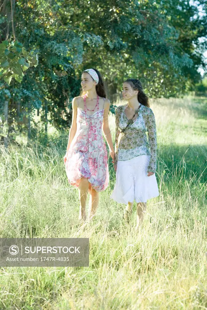 Two young women walking through field
