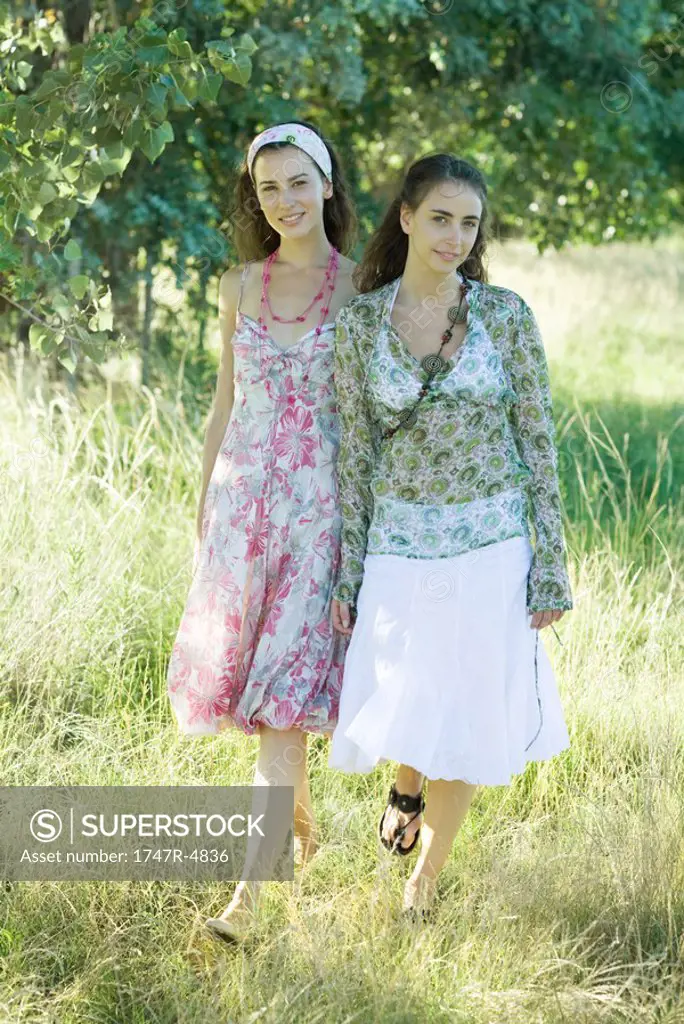 Two young women walking through field
