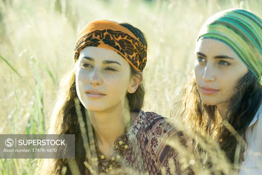 Two young women sitting in field