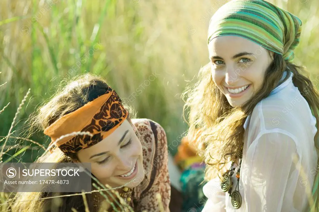 Two young women sitting in field