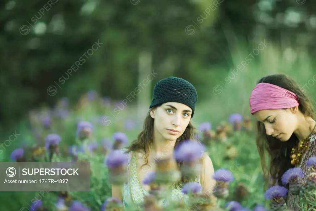 Young women standing in field of thistle