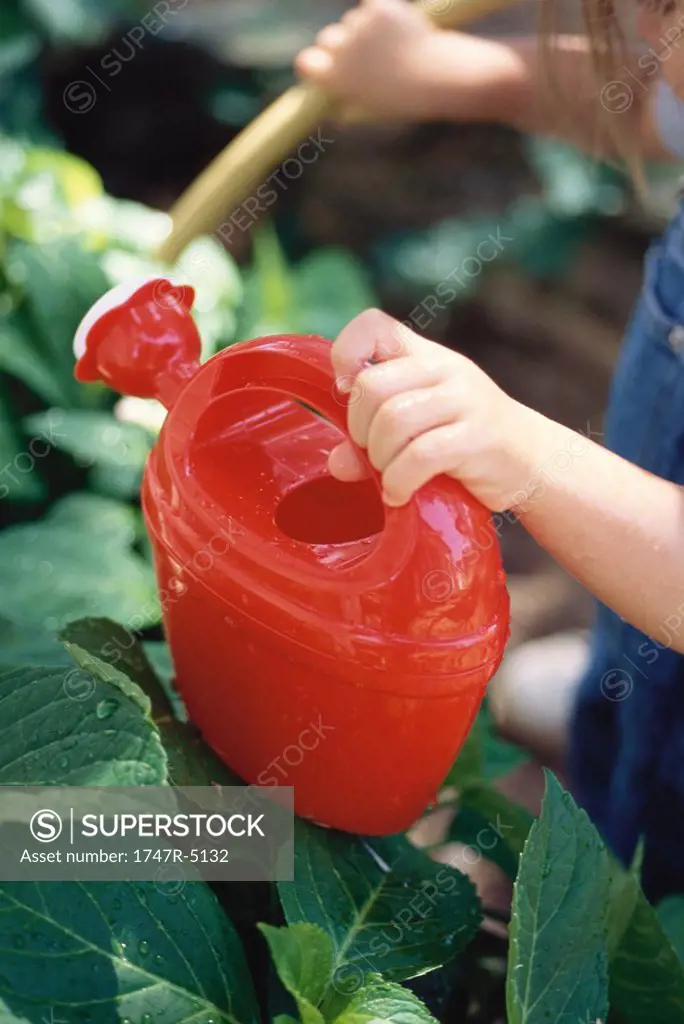 Child holding watering can, cropped view