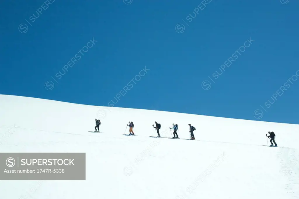 Skiers going up snowy slope, single file