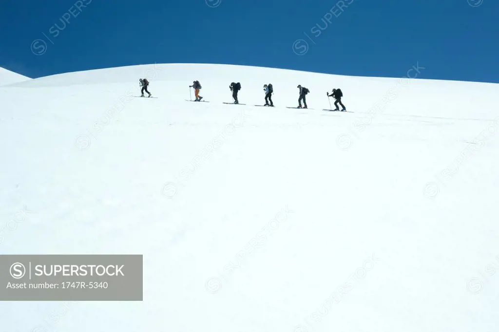 Skiers going across snowy landscape, single file