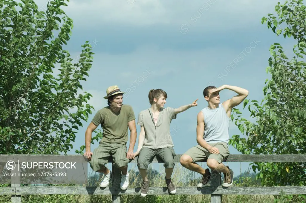 Hikers sitting on wooden fence, looking toward distance