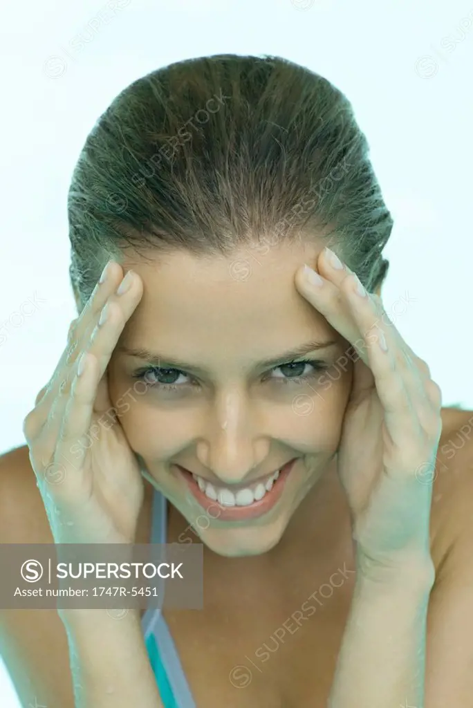 Young woman in pool, hands on side of face