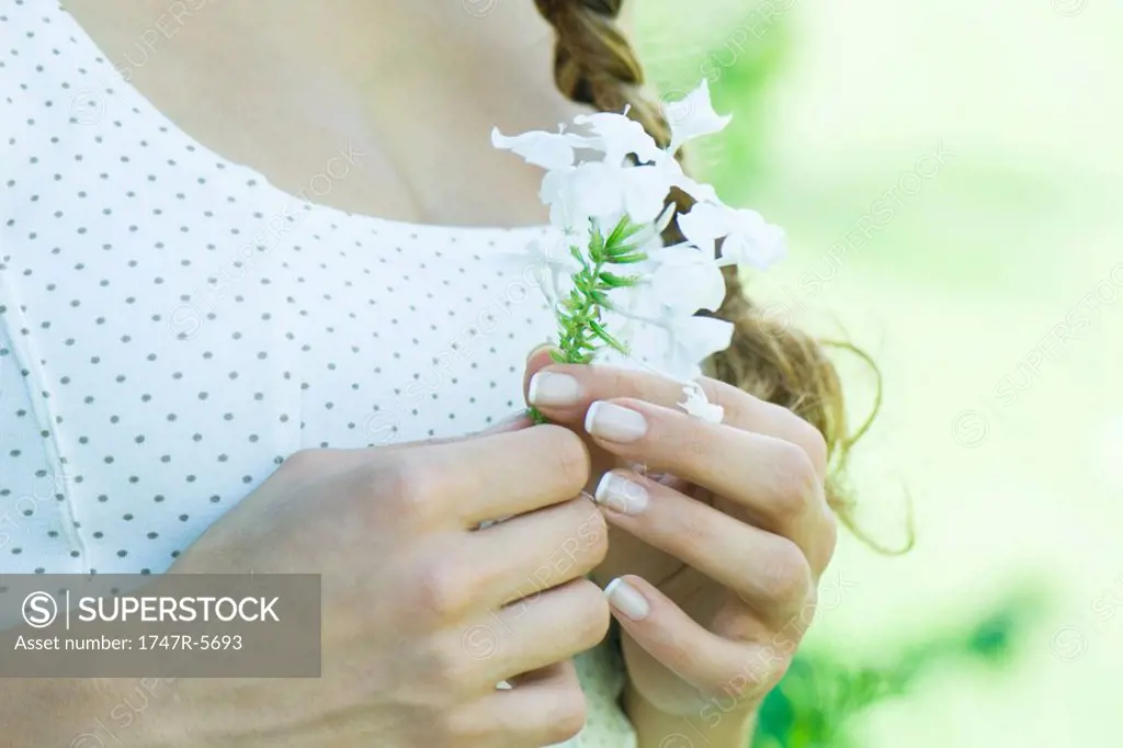 Woman holding flower, close-up of hands and chest