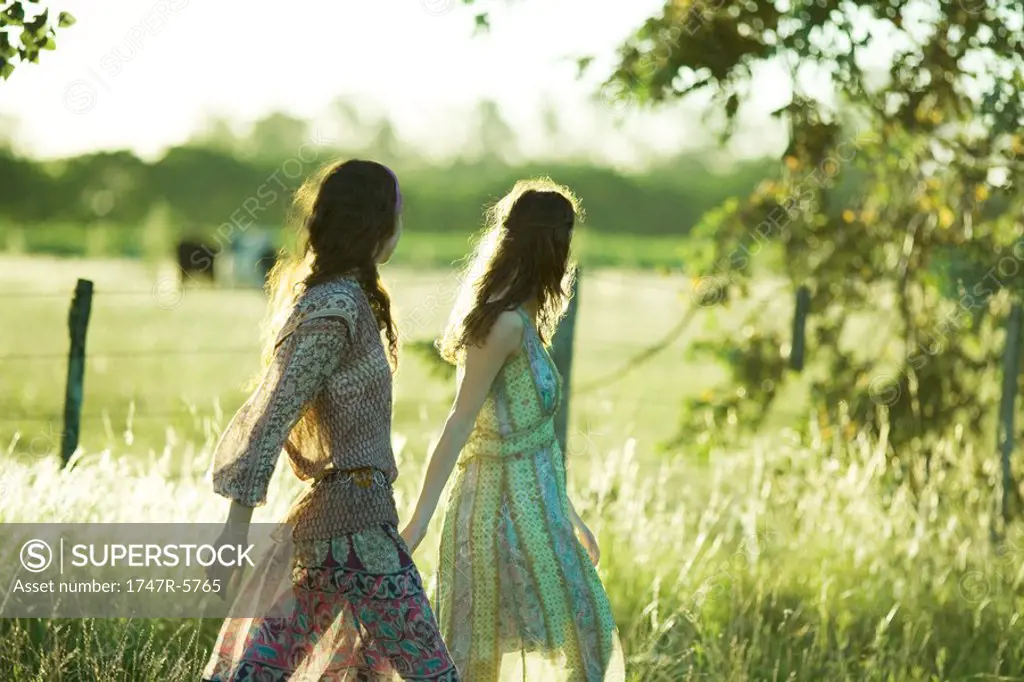 Young hippie women walking through field