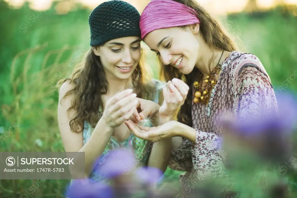 Young hippie women looking at dandelion seed heads