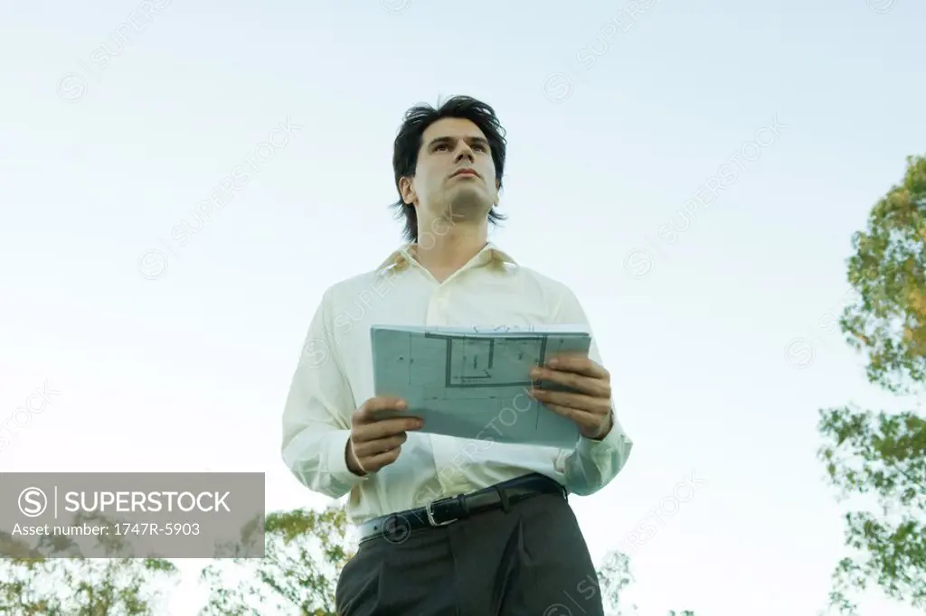 Man holding blueprints, low angle view
